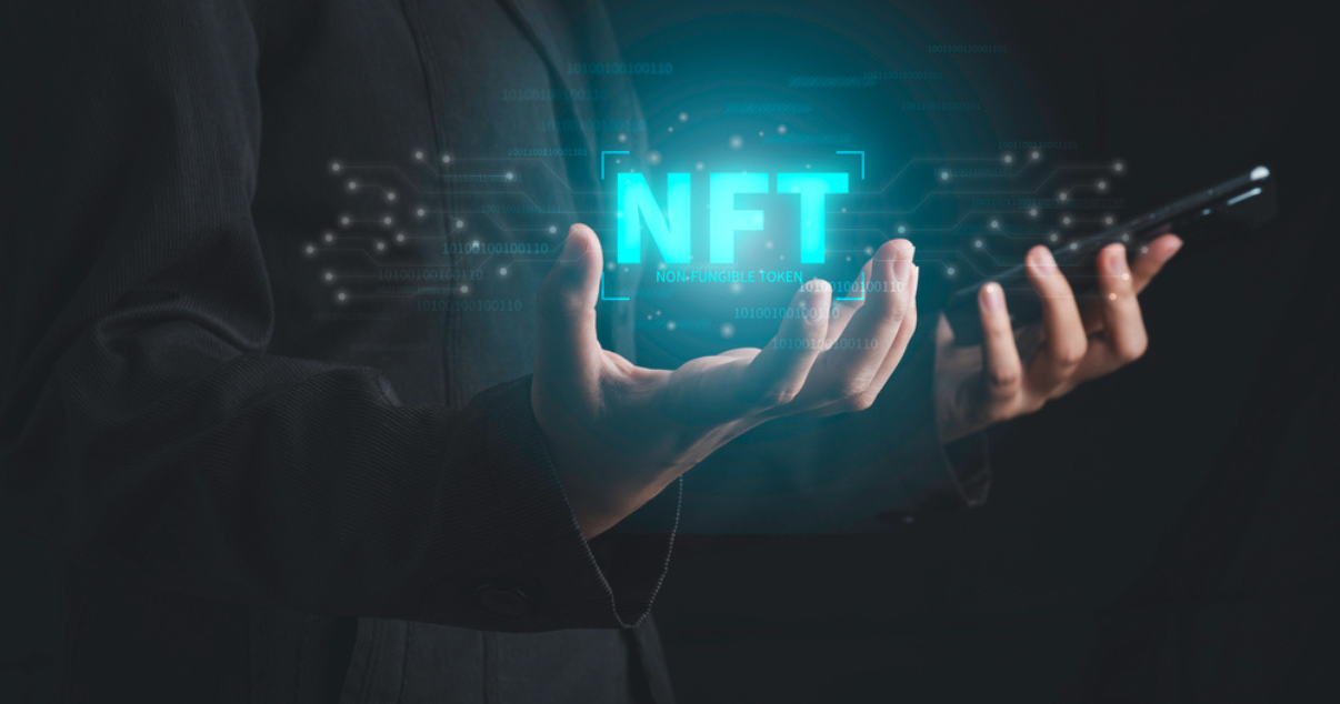 Hands holding cellphone and NFT logo 