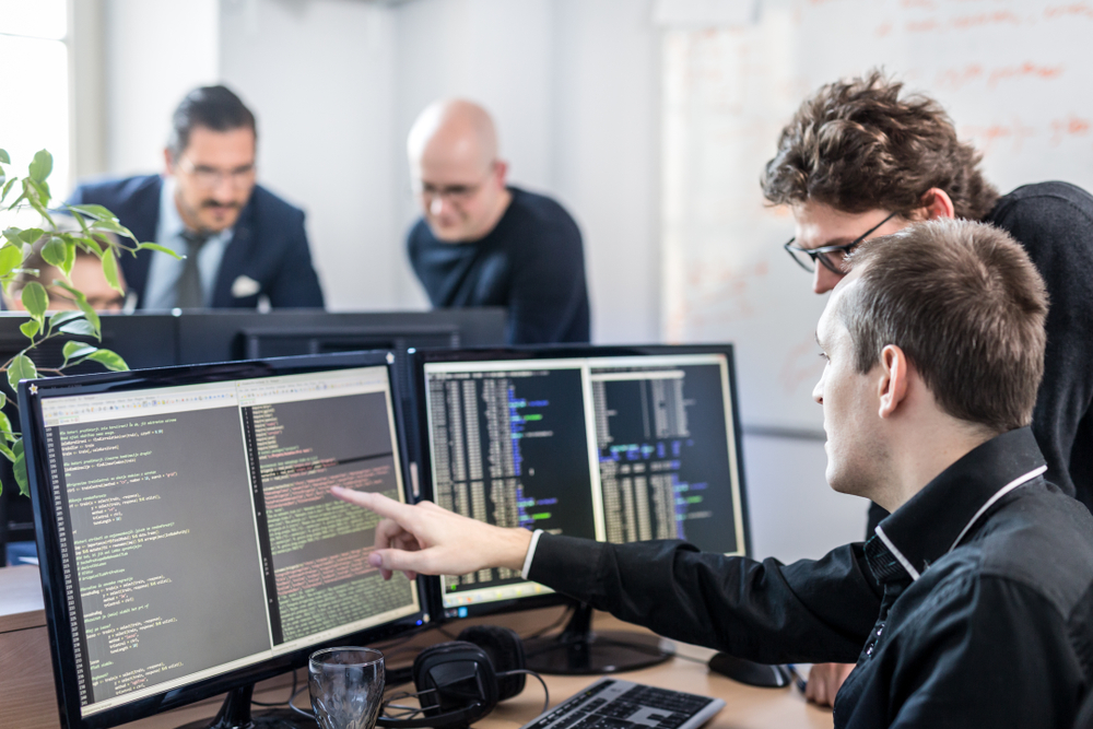 man working in office, with several screens - related to staff augmentation